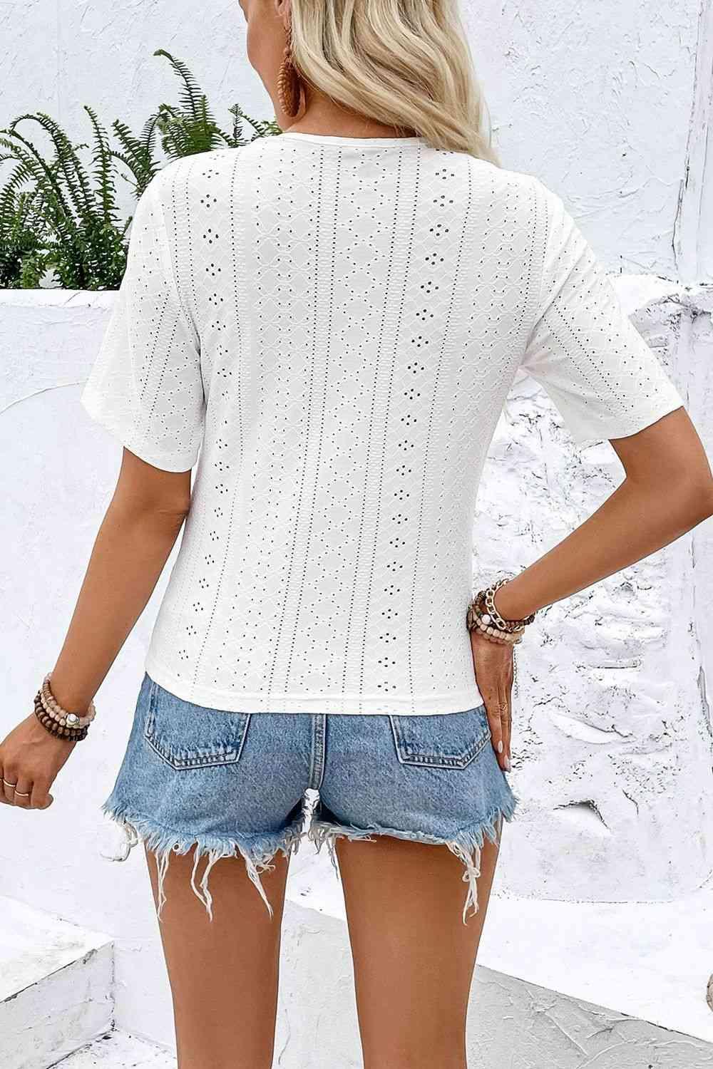 a woman wearing a white sweater and denim shorts