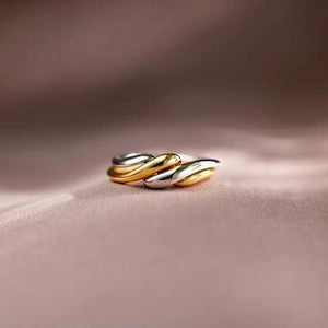 two gold and silver rings sitting on top of a table