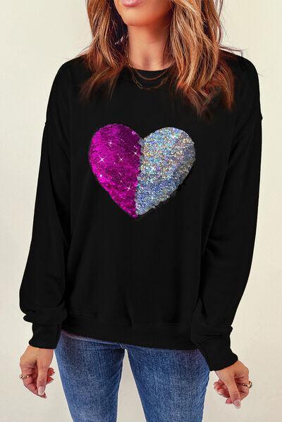 a woman wearing a black sweatshirt with a heart on it