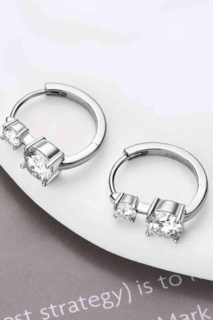 a pair of silver hoop earrings sitting on top of a white plate