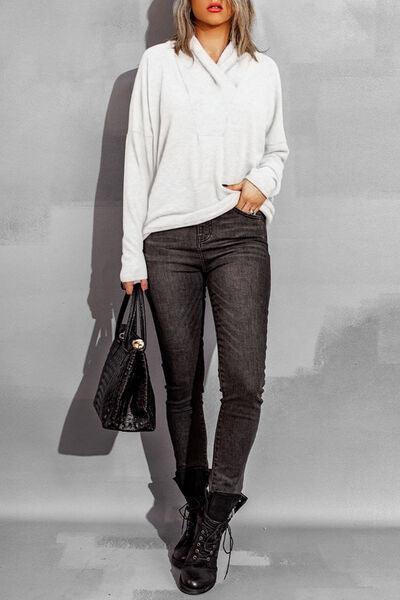 a woman in a white sweater and black pants
