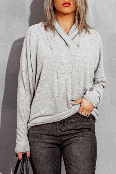 a woman in grey sweater and jeans holding a black bag