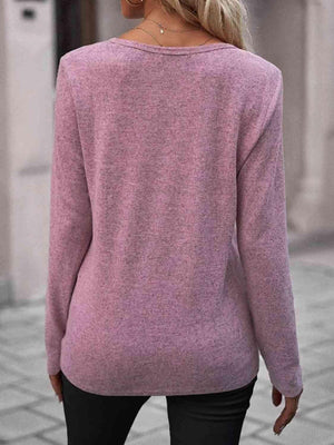 a woman wearing a pink sweater and black pants