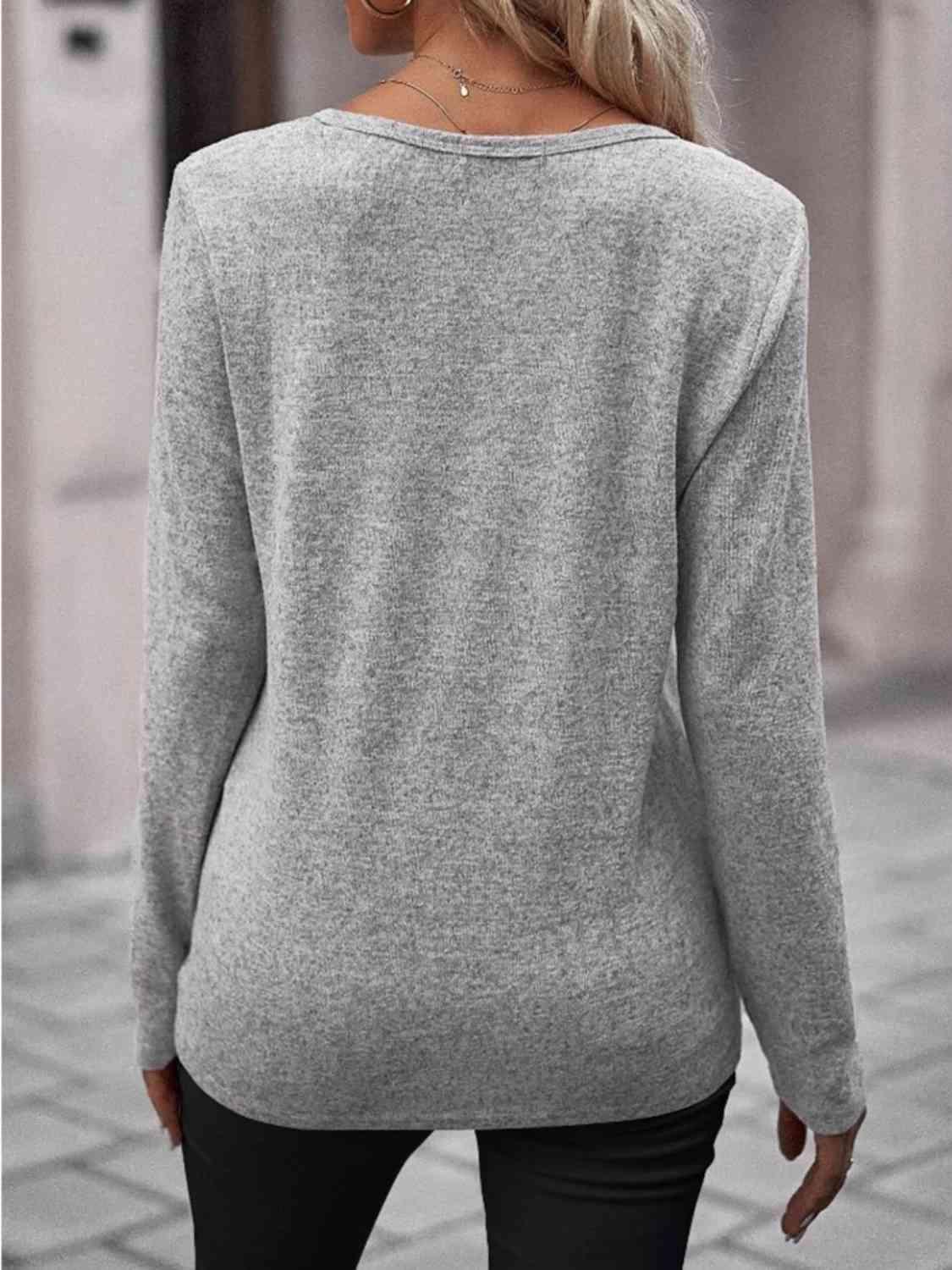 a woman wearing a grey sweater and black pants