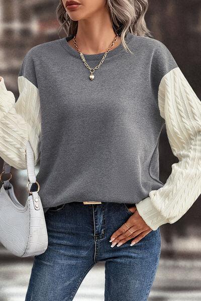 a woman wearing a gray and white sweater and jeans