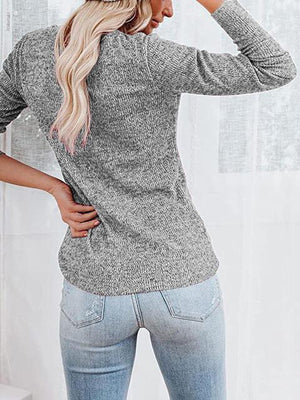 a woman wearing a gray sweater and jeans