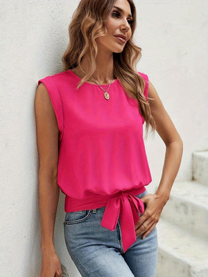 a woman leaning against a wall wearing a pink top
