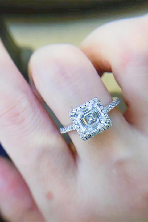 a close up of a person's hand holding a diamond ring