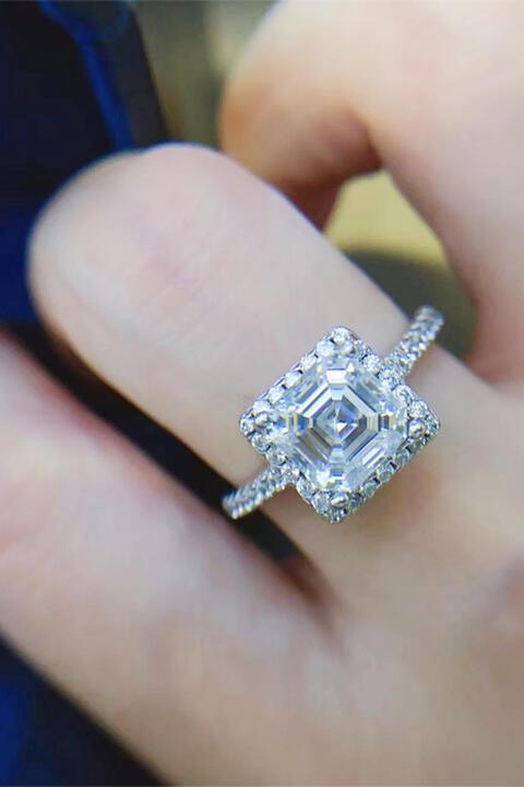 a close up of a person's hand holding a diamond ring