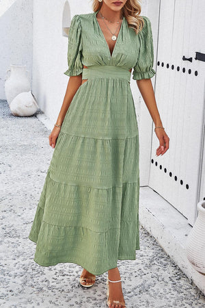 a woman in a green dress standing in front of a door