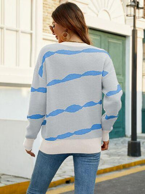 a woman walking down a street wearing a blue and white sweater
