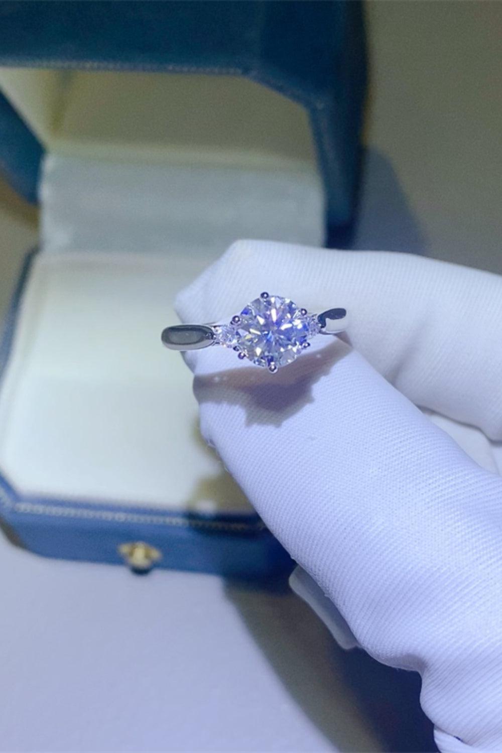 a woman's hand holding a ring with a diamond in it
