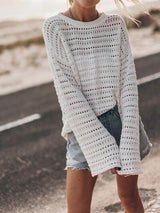 a woman wearing a white sweater and denim shorts
