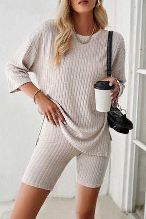 a woman in a sweater and shorts holding a coffee cup