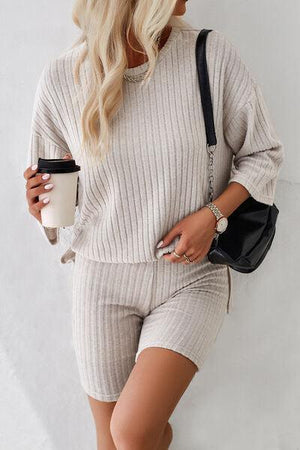 a woman in a sweater and shorts holding a coffee cup