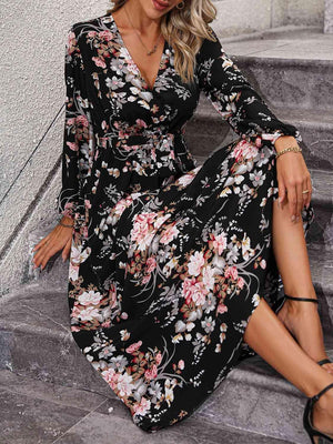 a woman in a black floral dress sitting on steps