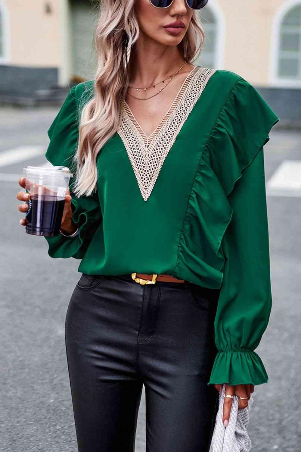 a woman wearing a green blouse and black pants