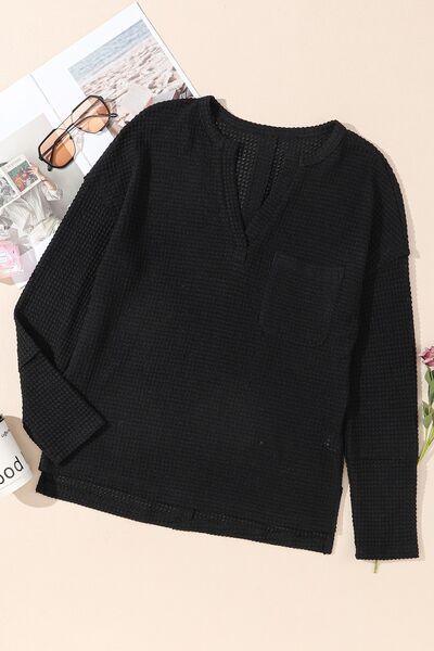 a black sweater sitting on top of a table next to a magazine
