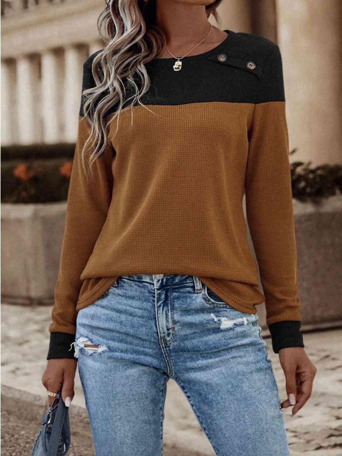 a woman wearing a brown sweater and ripped jeans