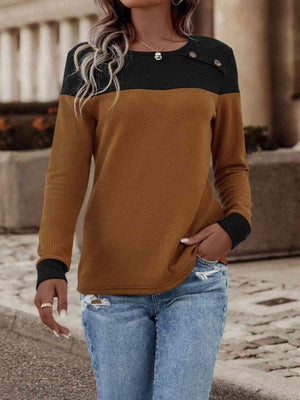 a woman wearing a brown and black sweater and ripped jeans