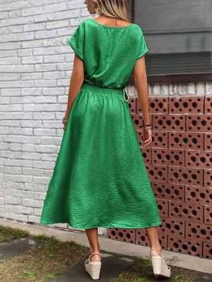 a woman in a green dress standing on a sidewalk