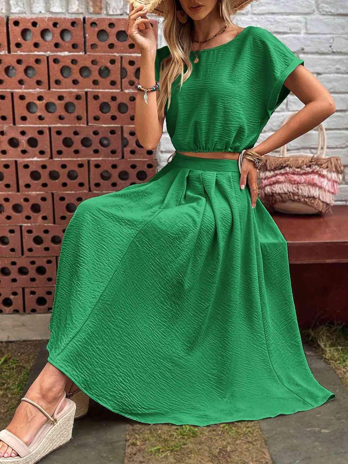 a woman sitting on a bench wearing a green dress
