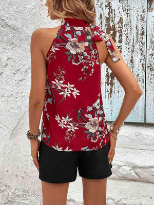 a woman wearing a red floral top and black shorts