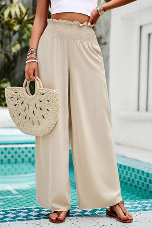 a woman standing next to a pool holding a purse