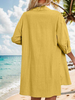 a woman standing on a beach wearing a yellow dress