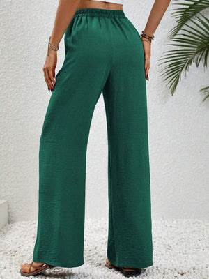 a woman in a white top and green pants