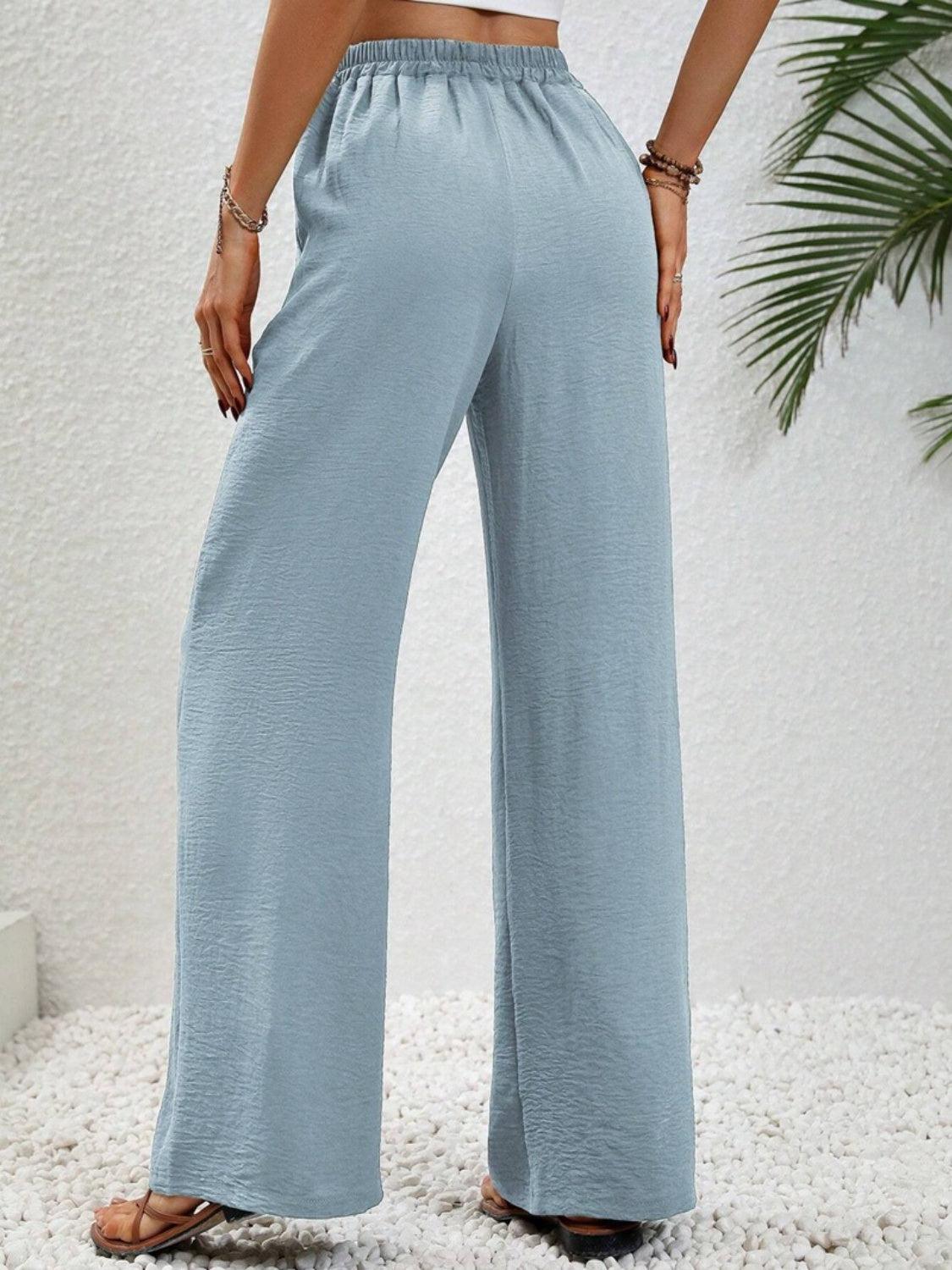 a woman wearing a crop top and wide legged pants