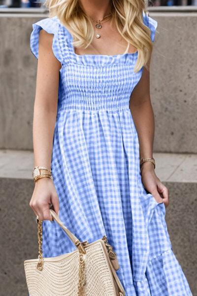 a woman in a blue gingham dress carrying a straw bag