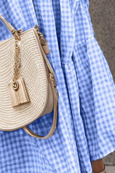 a woman in a blue dress carrying a straw bag