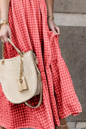 a woman in a red and white dress carrying a straw bag