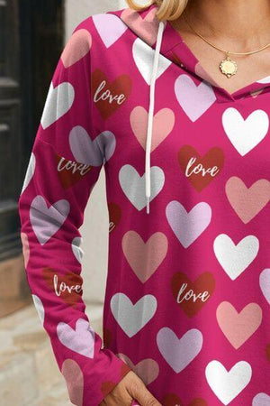 a woman wearing a pink hoodie with hearts on it