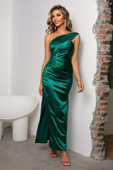 a woman in a green dress leaning against a wall