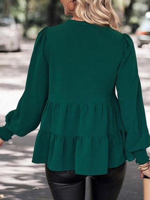 a woman wearing a green blouse and black pants