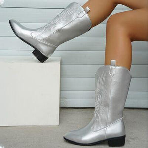 a close up of a woman's legs wearing silver cowboy boots