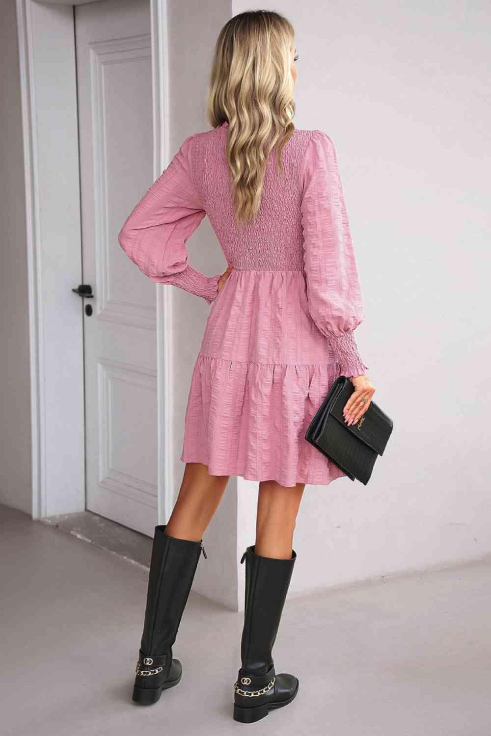 a woman wearing a pink dress and black boots