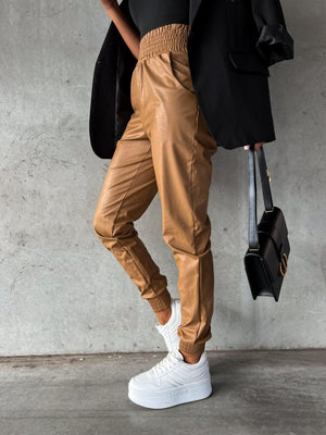 a woman in a black top and tan pants