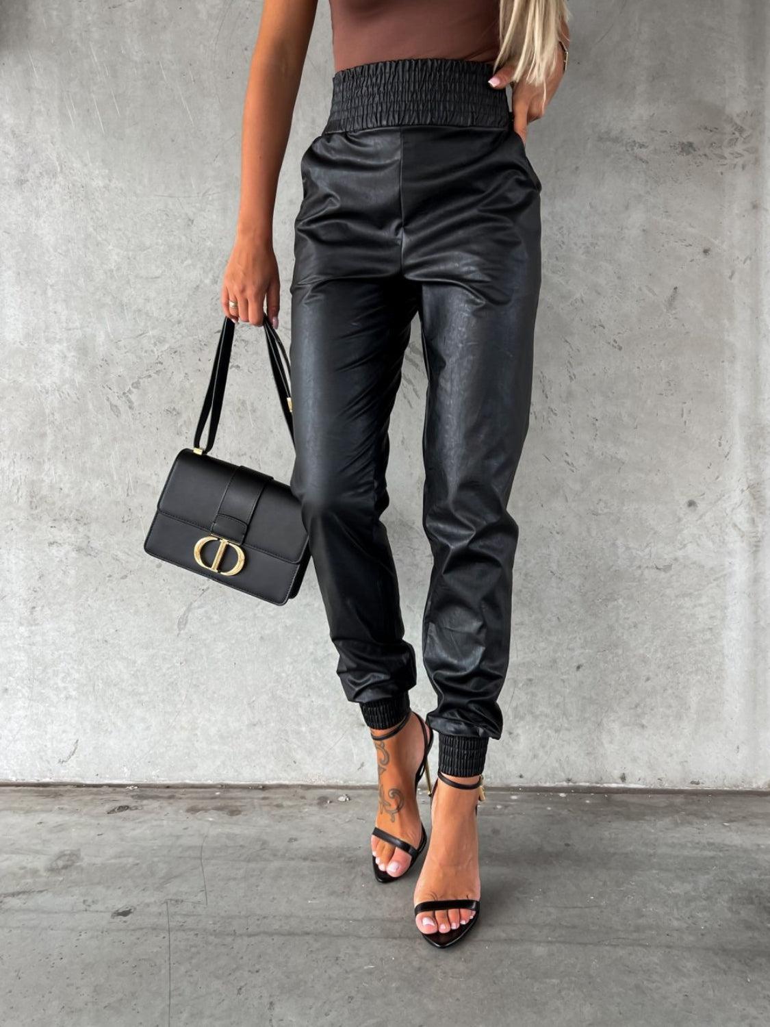 a woman in a brown top and black pants holding a black bag