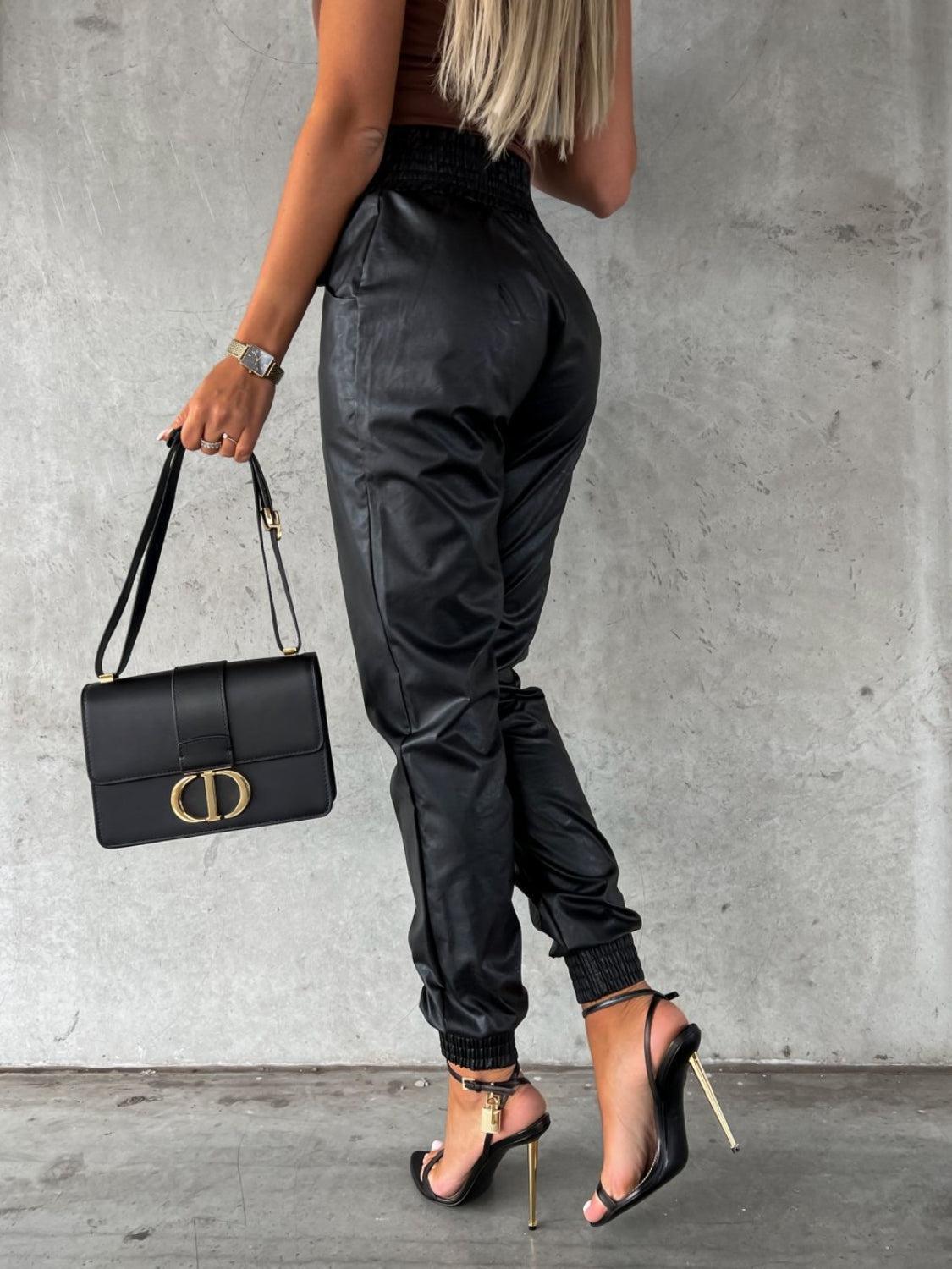 a woman holding a black handbag and wearing high heels