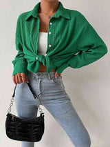 a woman wearing a green shirt and jeans holding a black purse