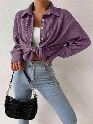 a woman wearing a purple shirt and jeans holding a black purse
