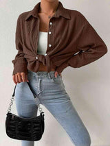 a woman wearing a brown shirt and jeans holding a black purse