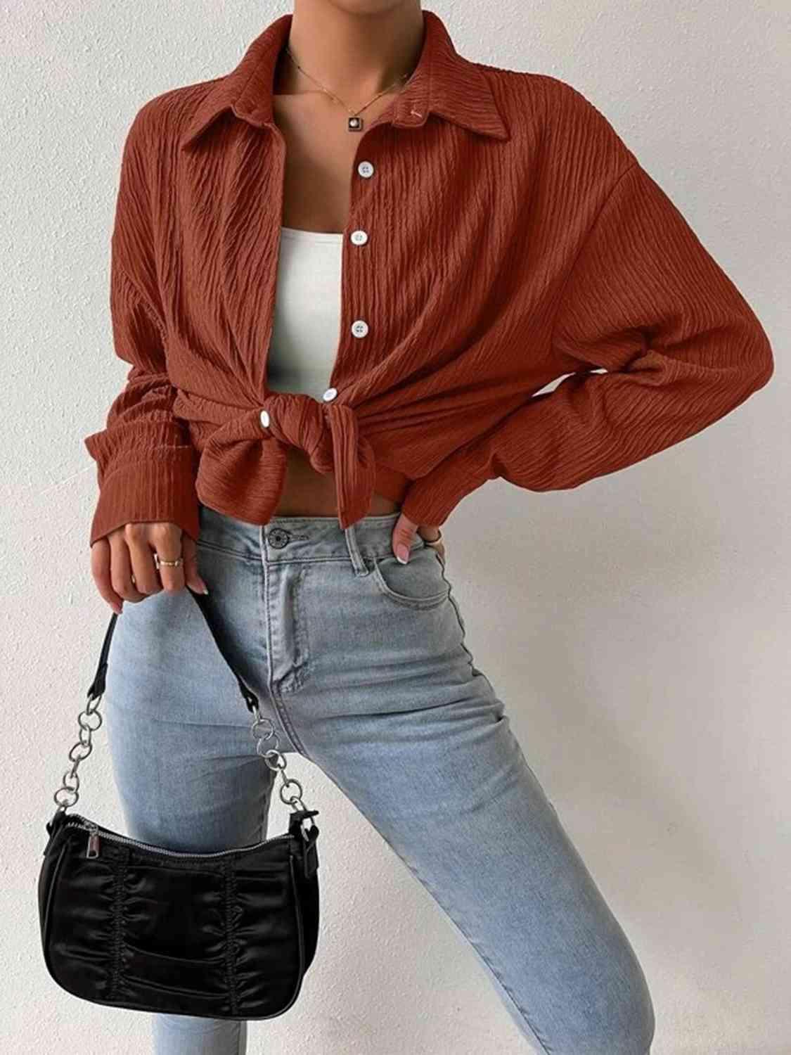 a woman wearing a red shirt and jeans holding a black purse
