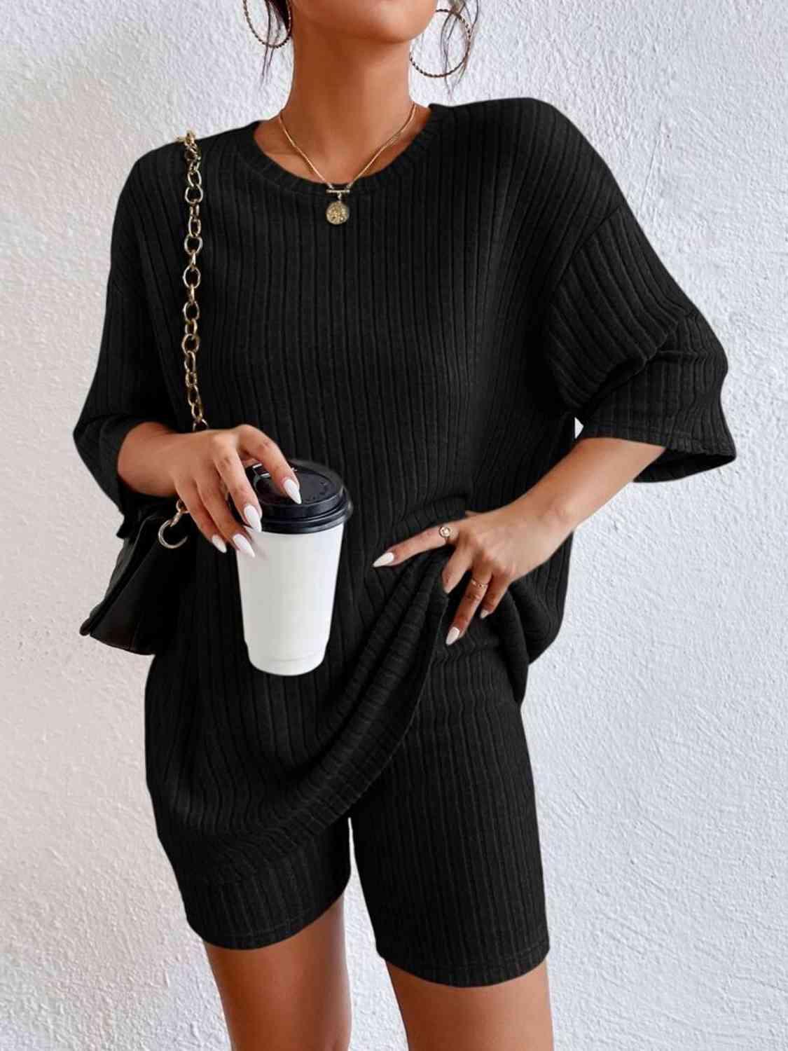 a woman wearing a black sweater and shorts holding a coffee cup