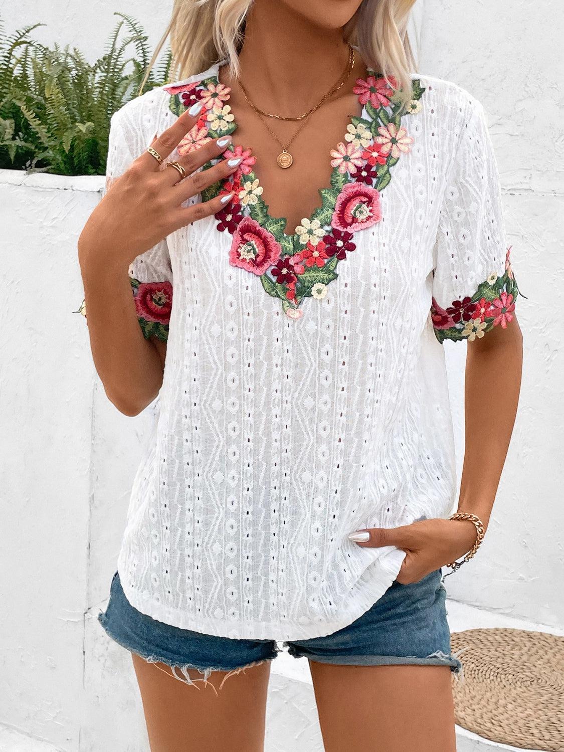 a woman wearing a white top with flowers on it