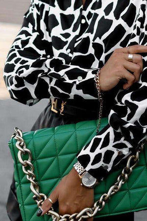 a woman in a black and white shirt holding a green purse