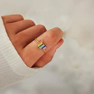 a woman's hand holding a ring with a rainbow design on it